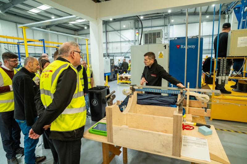 Visitors pictured being taken on a tour around Preformed Windings' new Unit J facility, with a member of staff demonstrating a coil